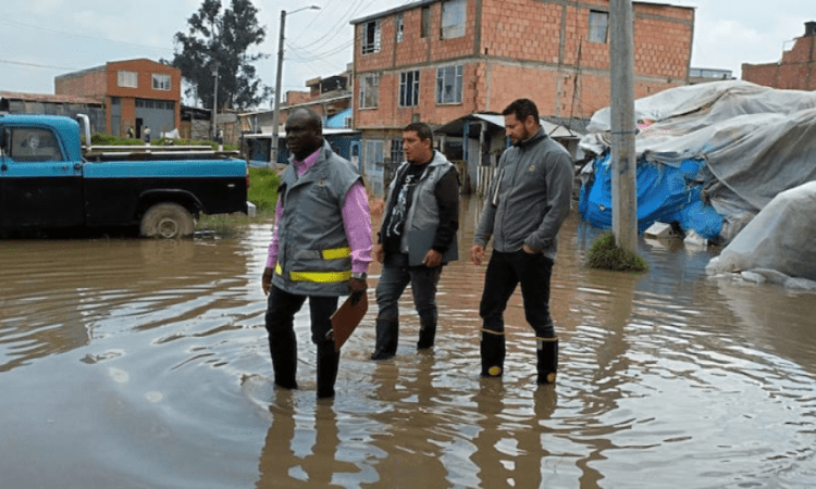 Imagen de tres personas caminando en un charco