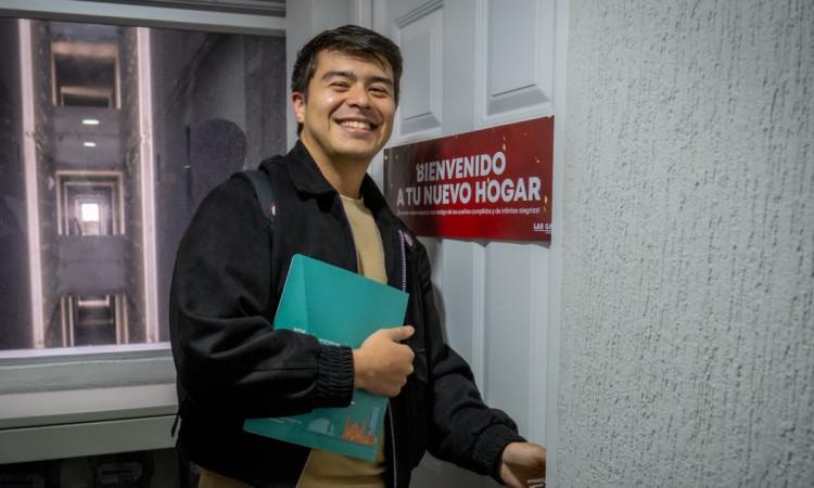 Foto que muestra una persona sonriente abriendo una puerta