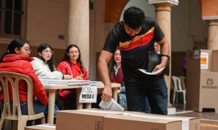 Hombre joven depositando su voto en una urna.