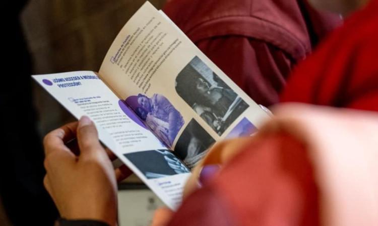 Manos de mujer sosteniendo un folleto de la SDMujer sobre cómo acceder a medidas de protección