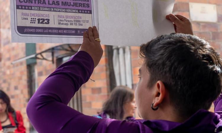 Mujer con un cartel sobre rutas de atención para mujeres víctimas de violencia.