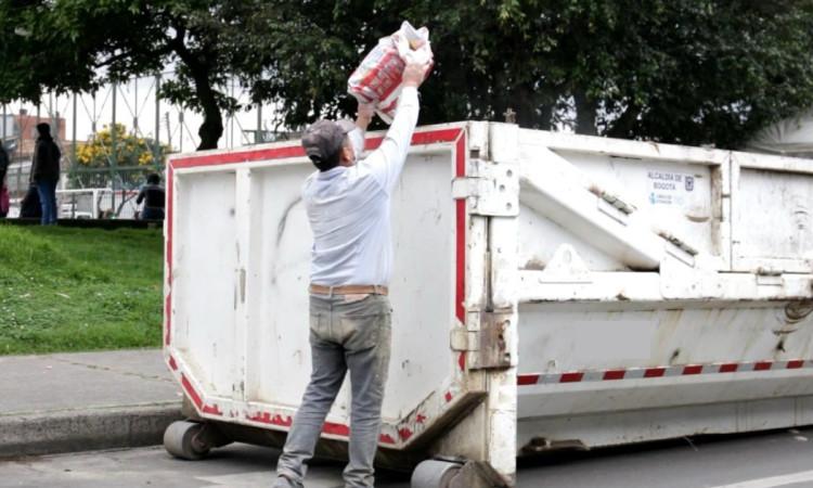 Foto que muestra una persona dejando una bolsa en un Ecopunto