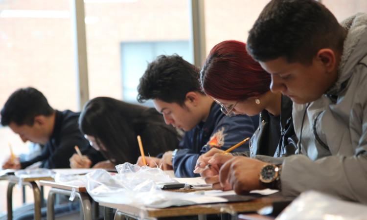 Foto que muestra personas escribiendo en una hoja 