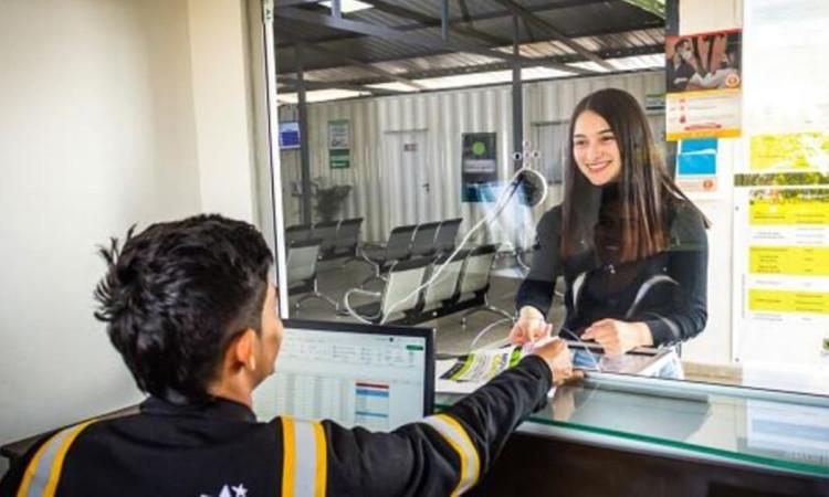 Foto de una mujer y un hombre en una ventanilla de atención de servicios de movilidad en Bogotá.