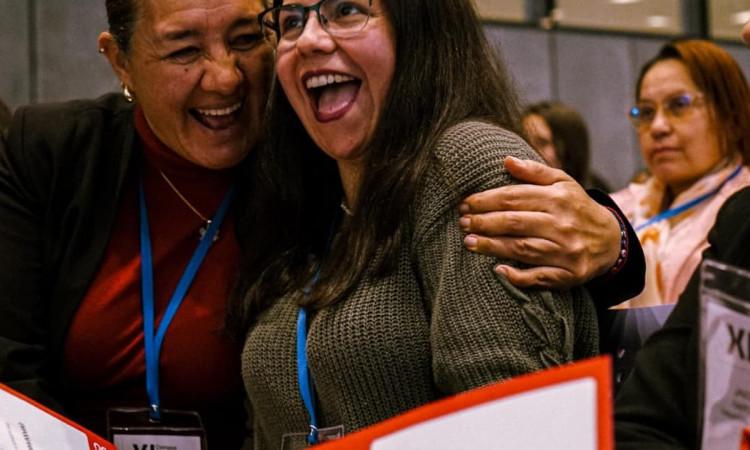 Foto de mujeres abrazandose y sonriendo.