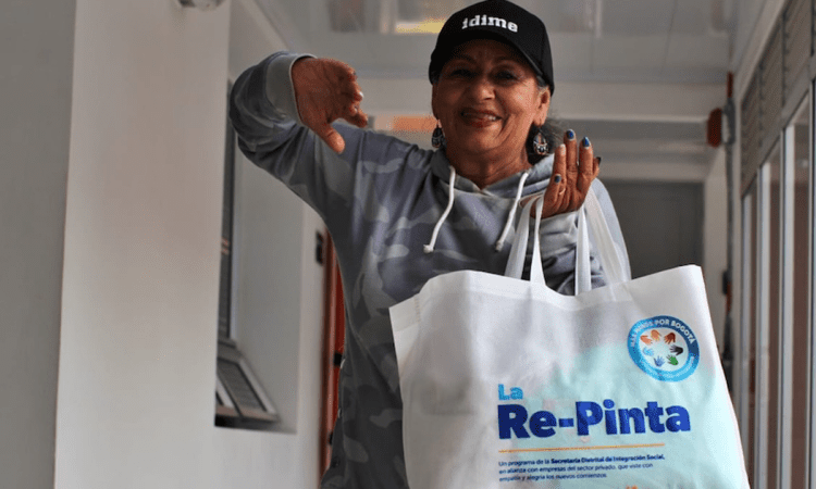 Imagen de una mujer sonriendo y sosteniendo un talego con ropa