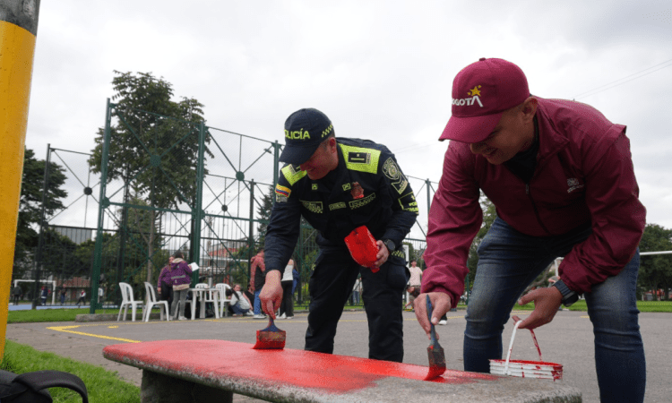 Imagen de varias personas pintando una banca de parque