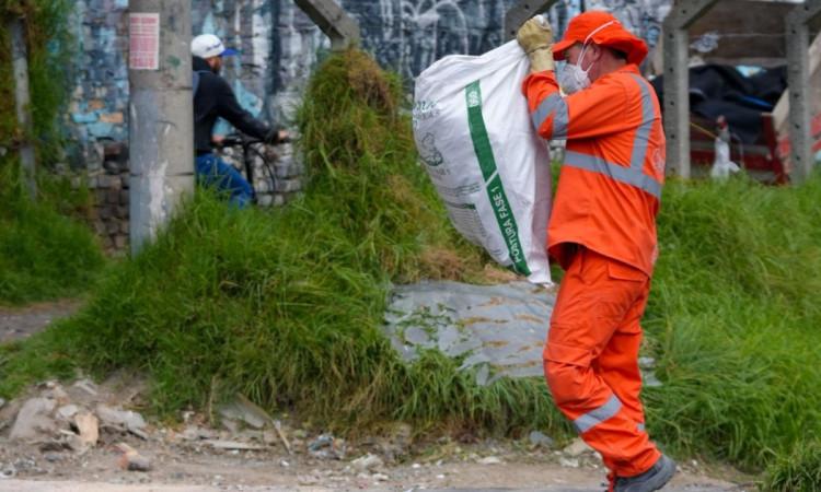 Foto que muestra una persona cargando una bolsa con residuos