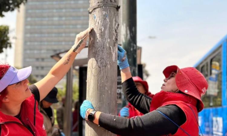 Funcionarios del DADEP limpiando un poste de luz de publicidad no permitida.