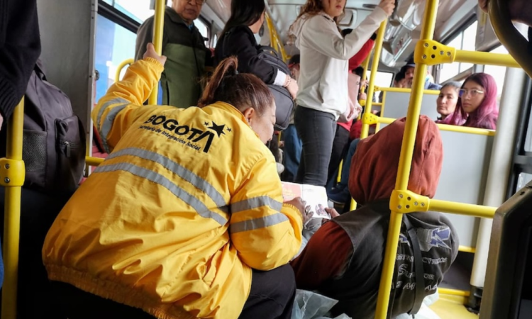 Imagen de una funcionaria atendiendo a un habitante de calle en un bus de TransMilenio