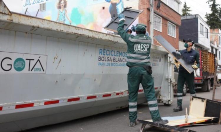 Foto que muestra dos personas dejando residuos en un carro recolector