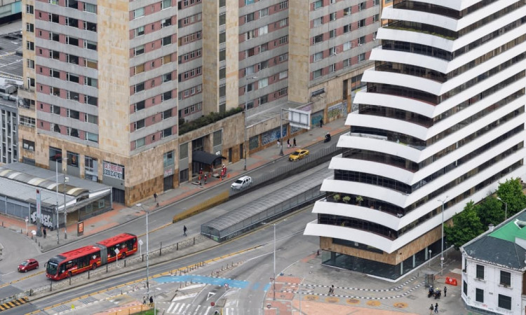Avenida bogotana con buses TransMilenio, edificios altos y cruces peatonales desde arriba