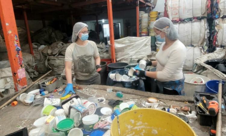 Foto que muestra dos personas con gorros y tapabocas reciclando 