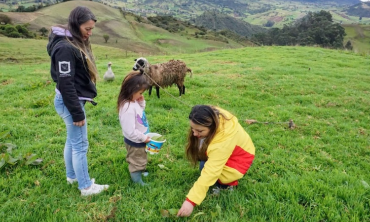 Imagen de una funcionaria junto con una señor y una niña en una área rural