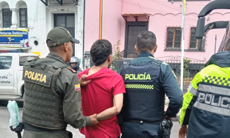 Hombre capturado durante el operativo, rodeado de tres policías.
