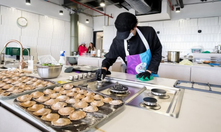 Persona prepara empanadas en aula culinaria del CEFE Cometas de Suba con estufas, bandejas y utensilios educativos