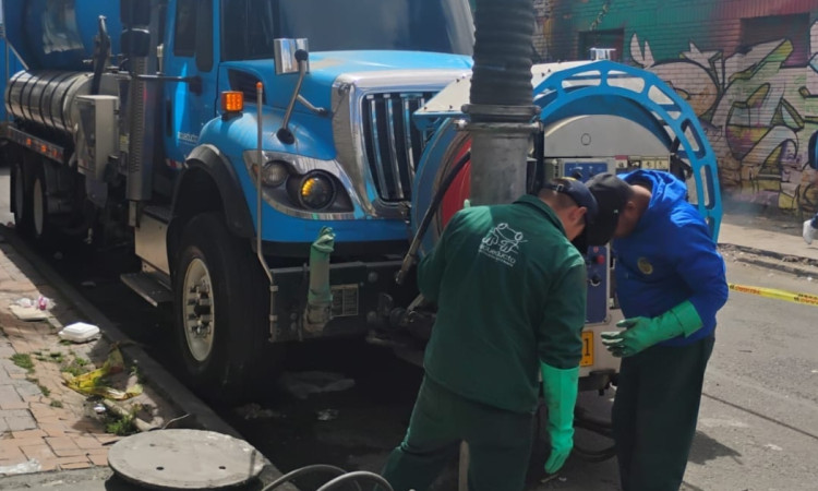 Foto que muestra personas con el uniforme del Acueducto de Bogotá trabajando en una alcantarilla