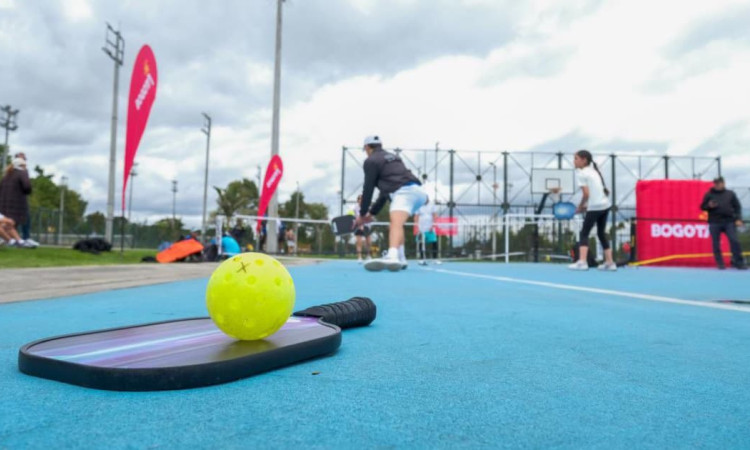 Raqueta de pickleball y una bola verde en un cancha para practicar este deporte
