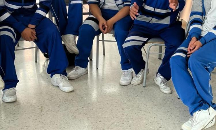 Estudiantes de colegio sentados en sillas.