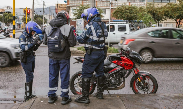 Foto de agentes de tránsito junto a un motociclista en Bogotá