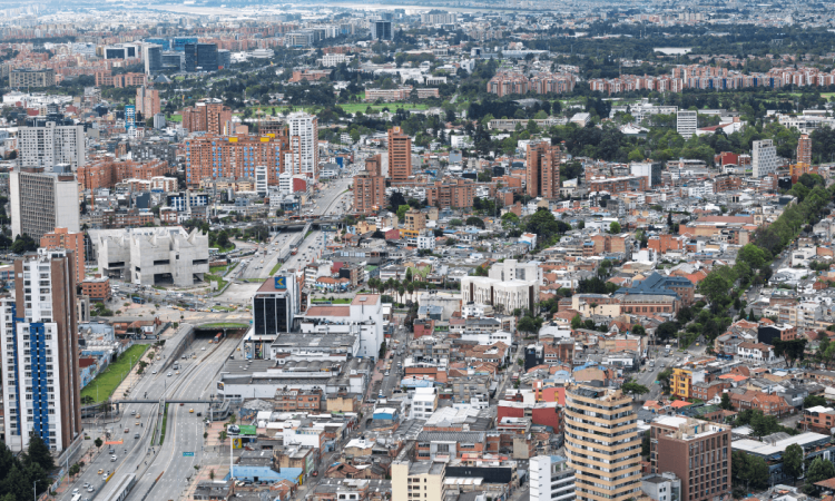 Vista panorámica de Bogotá con edificaciones residenciales y comerciales, avenidas principales y amplia expansión urbana observada desde gran altura.