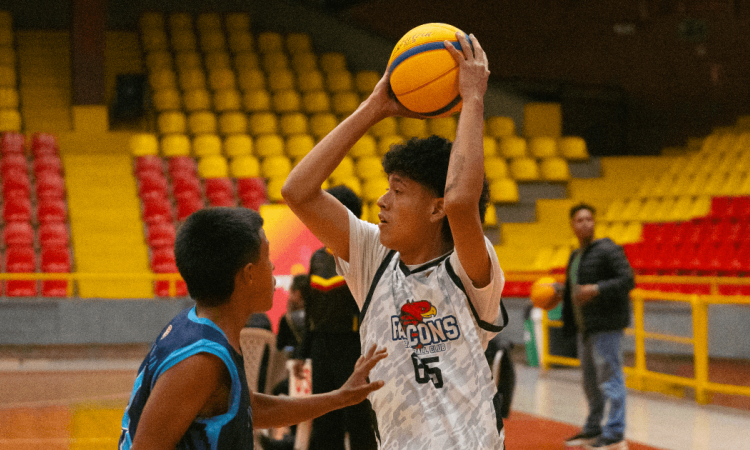 Jóvenes disputan partido de baloncesto en escenario deportivo cubierto de Bogotá.