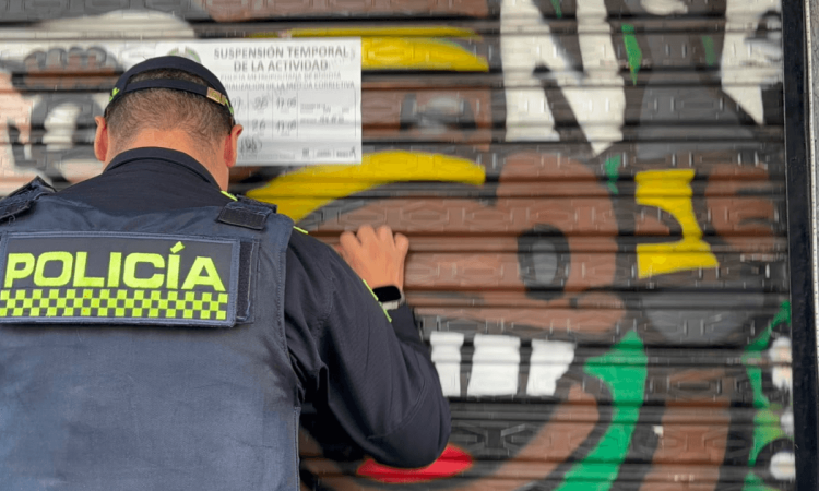 Policía pegando un aviso de suspensión temporal en un establecimiento del Siete de Agosto