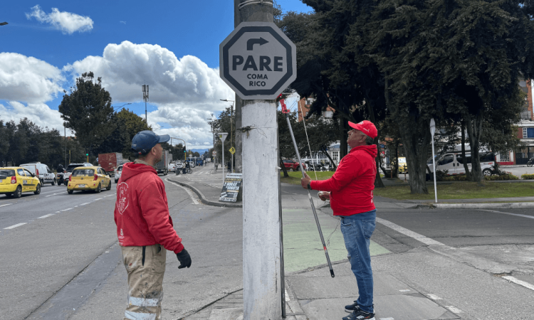Defensores del espacio público retirando un pendón ilegal del mobiliario público.
