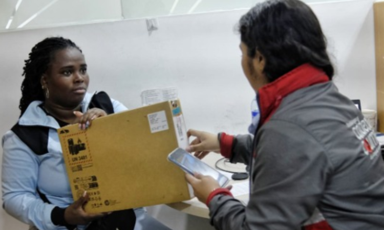 Imagen de una funcionaria entregando un computador a una mujer
