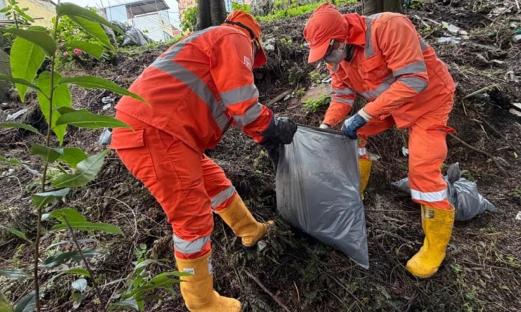 Foto que muestra dos personas con el uniforme de Aguas de Bogotá recogiendo residuos 