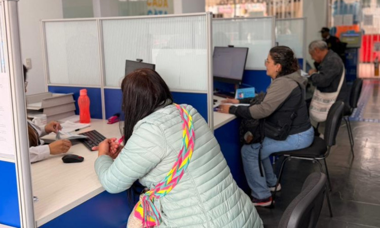 Foto que muestra tres personas sentadas frente a modulos de atención 