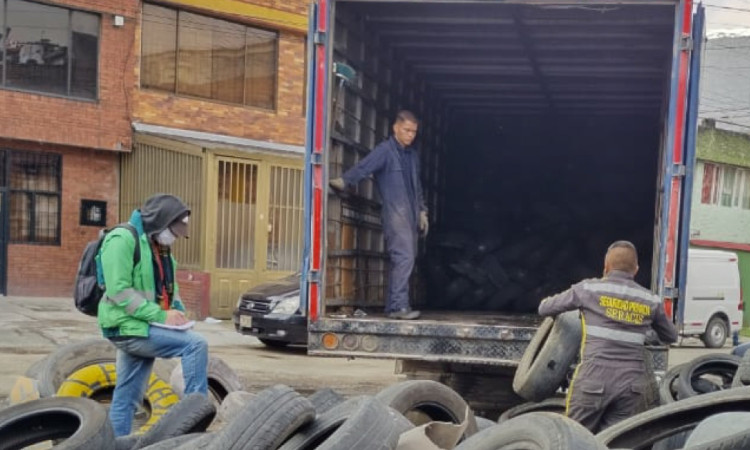 Foto que muestra personas recolectando llantas y colocandolas en un camión 
