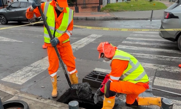 Foto que muestra dos personas con el uniforme de Aguas Bogotá limpiando un sumidero