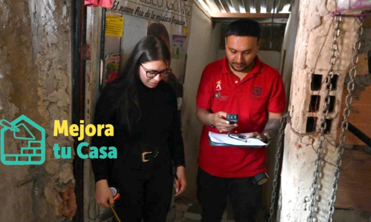 Foto que muestra dos personas una con un metro midiendo y la otra con un cuaderno tomando apuntes