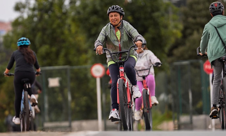 Personas recorren una ciclorruta en bicicleta durante una jornada recreativa rodeada de zonas verdes en Bogotá.