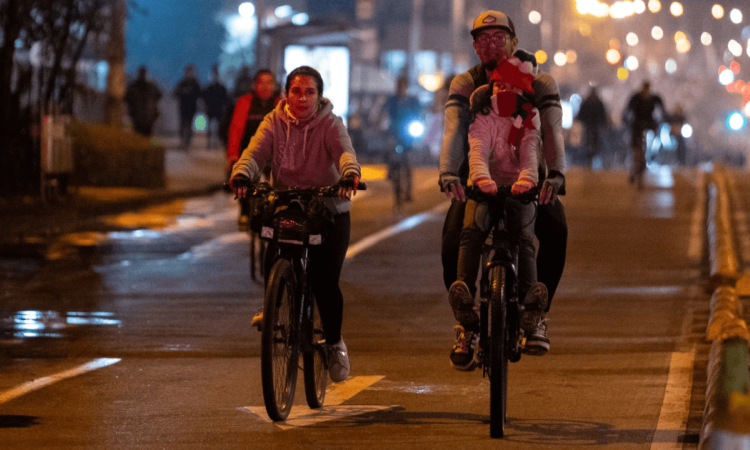 Personas recorren en bicicleta una vía iluminada de Bogotá durante una jornada de Ciclovía nocturna