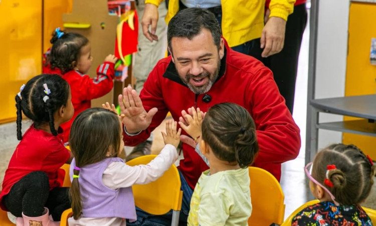 El alcalde Carlos Fernando Galán sonriendo con unos niños y niñas de un jardín infantil.