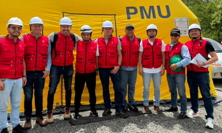 Foto que muestra un grupo de personas con chaleco rojo y casco blanco sonriendo 