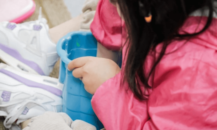 Niña jugando en el piso con un balde.