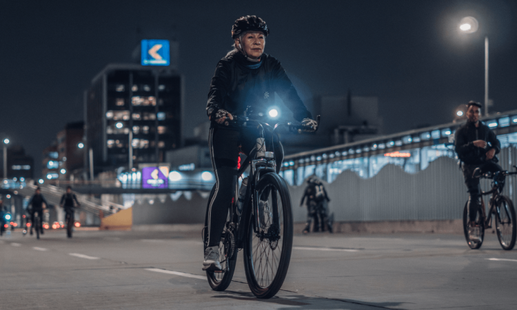 Mujer transita en bicicleta en calle de Bogotá durante Ciclovía Nocturna.