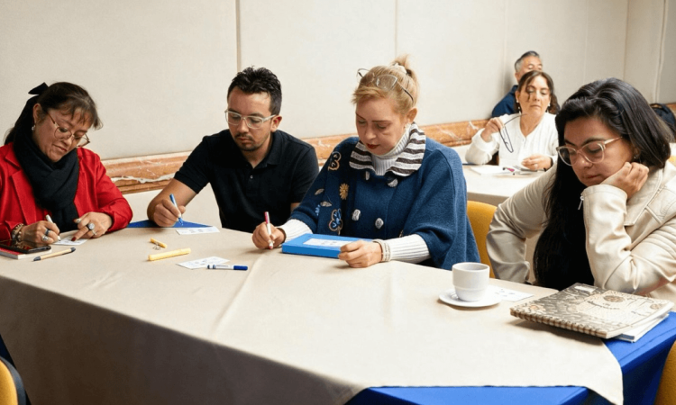 Foto que muestra personas sentadas escribiendo en un escritorio 