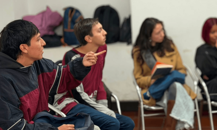 Foto que muestra dos hombres y dos mujeres sentados en escritorios dentro de un salón