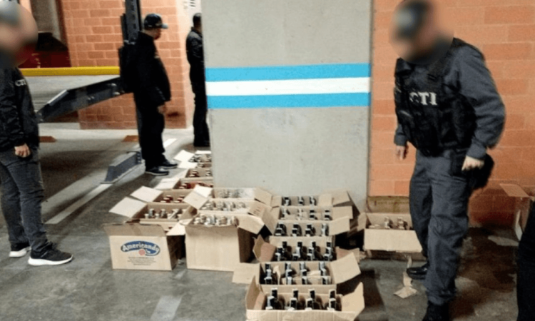 Foto que muestra cajas con licor en el piso y personal de la Fiscalía 