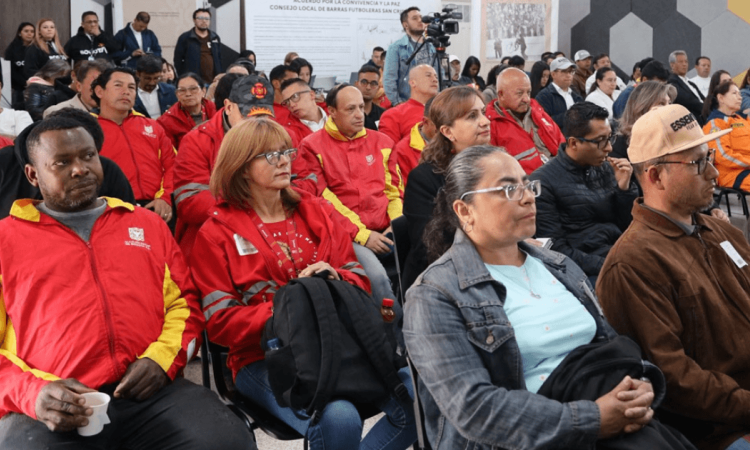 Personas sentadas en filas de sillas durante un encuentro ciudadano en un auditorio.