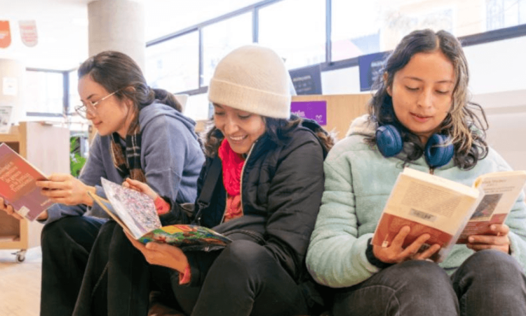 Imagen de 3 mujeres leyendo libros en bibliotecas públicas de Bogotá
