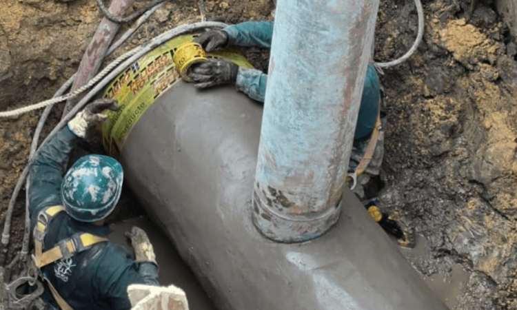 Foto que muestra dos personas del Acueducto de Bogotá reparando una tubería
