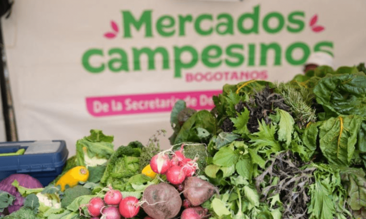 Productos agrícolas frescos, entre ellos rábanos, remolachas, lechugas y otras hortalizas, exhibidos en un puesto de Mercados Campesinos Bogotanos