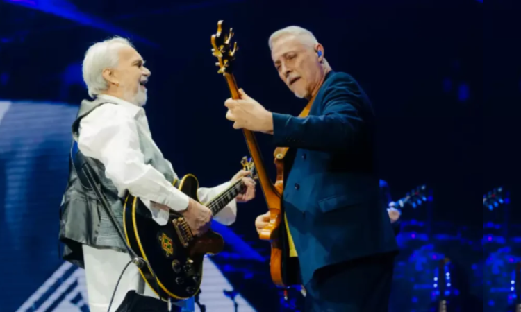 Imagen de dos hombres mayores tocan guitarra en un escenario.