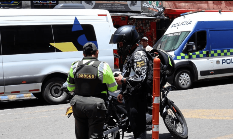 Policía registrando a una persona y verificando su motocicleta.