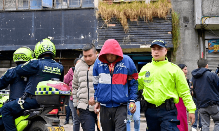 Foto de dos capturados esposados.